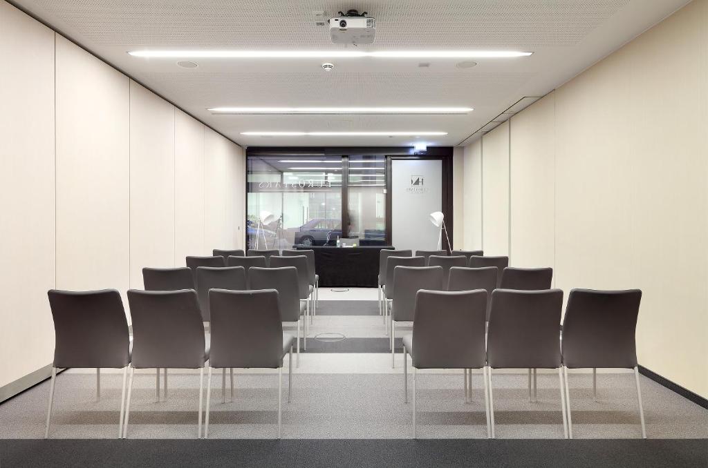 a conference room with black chairs and a podium at Eurostars Book Hotel in Munich