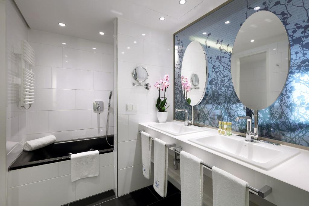 a bathroom with two sinks and a mirror at Eurostars Book Hotel in Munich