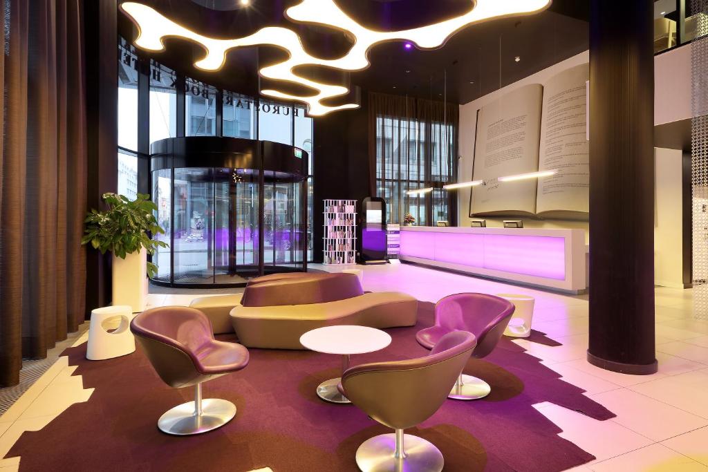 a lobby with a couch and a table and chairs at Eurostars Book Hotel in Munich