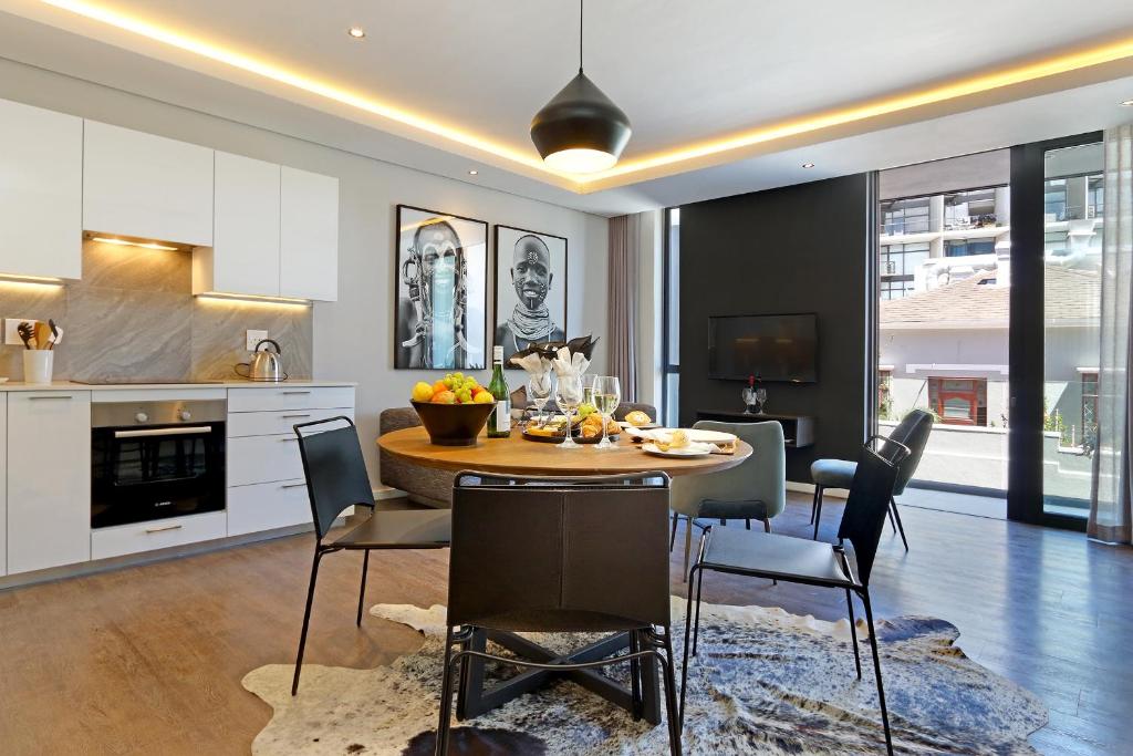 una cucina e una sala da pranzo con tavolo e sedie di Chelsea Luxury Suites by Totalstay a Città del Capo