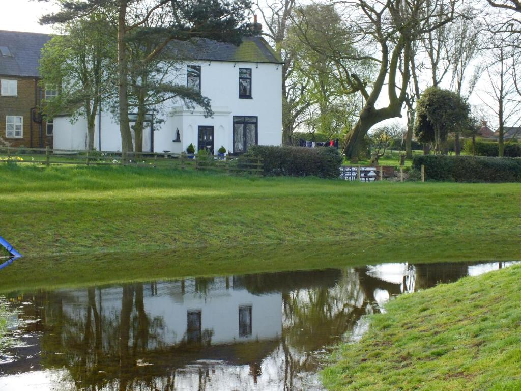 een huis met een reflectie in een vijver bij White House Farm Cottages in West Haddon