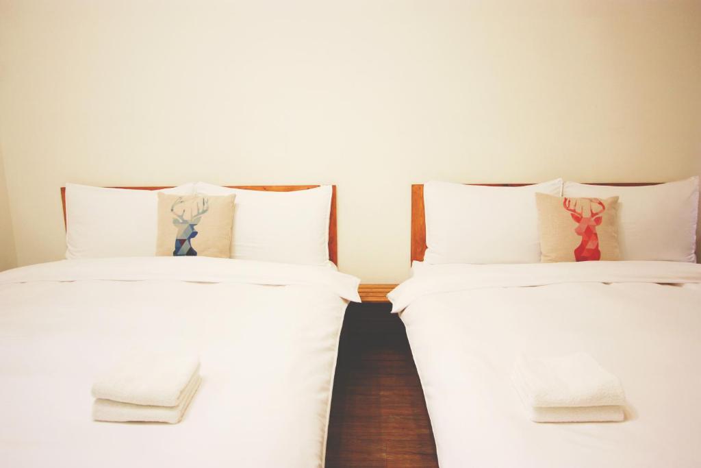 Habitación con 2 camas individuales y sábanas blancas. en OC Hostel, en Tainan
