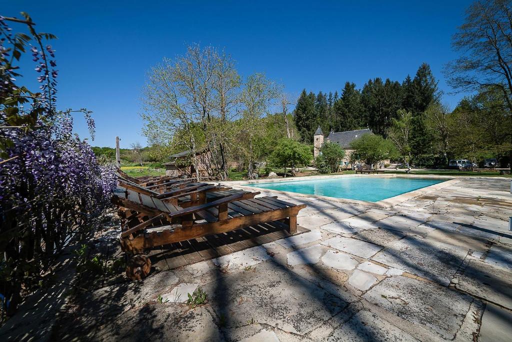 a wooden bench sitting next to a swimming pool at Le Moulin de Planiol in Le Vigan