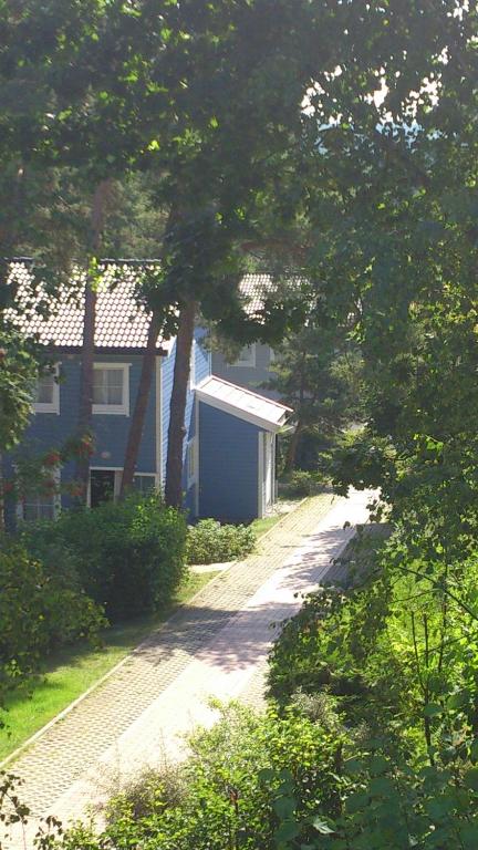 a road leading to a blue house with trees at ökologische Ferienanlage in Bansin