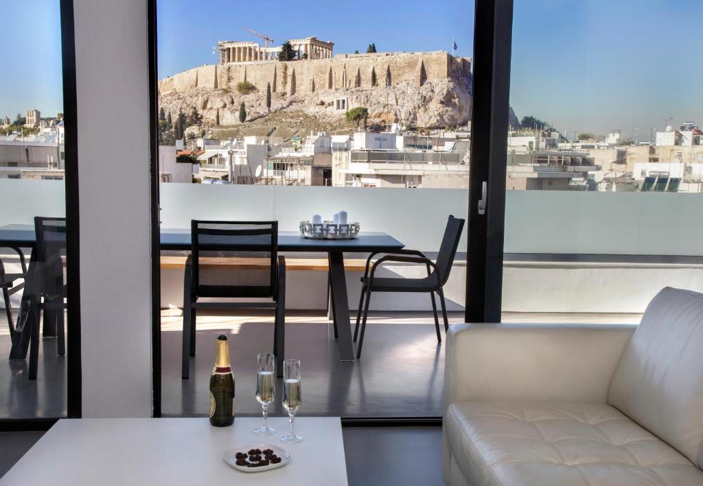 a living room with a table and chairs and a view ofhens at Luxury Penthouse touching the Acropolis by GHH in Athens