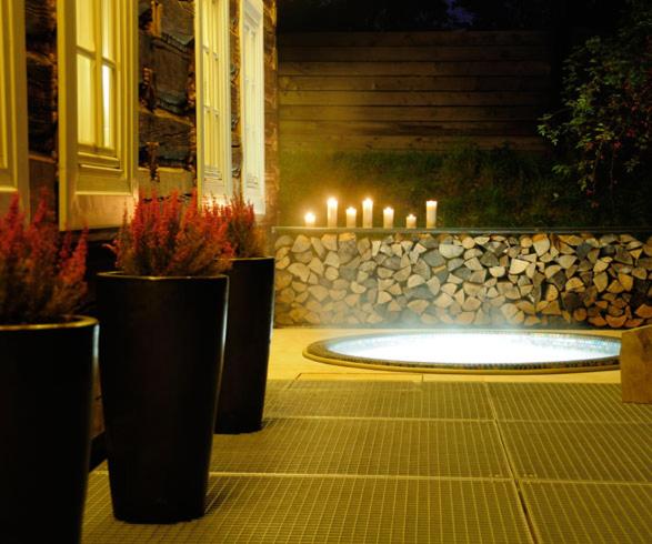 uma piscina iluminada com velas e vasos de plantas em Kacza Chata - willa z jacuzzi em Cracóvia