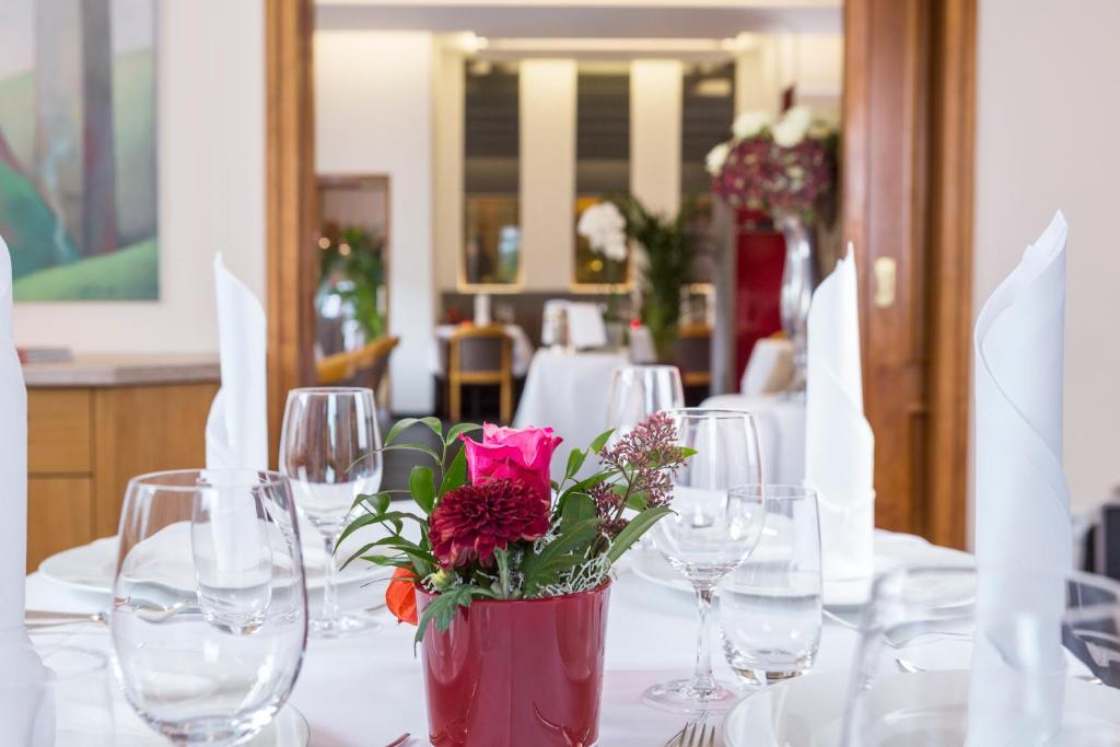 a table with wine glasses and a vase with flowers at Brackweder Hof in Bielefeld