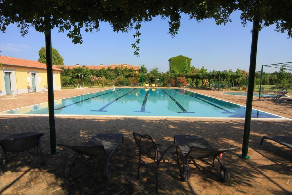 een zwembad met stoelen voor een gebouw bij Campastrello Sport Hotel Residence in Castagneto Carducci
