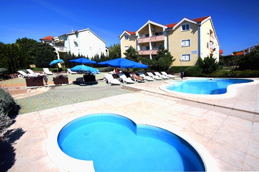 - une piscine avec des chaises et des parasols à côté d'un bâtiment dans l'établissement Dalmacia apartments, à Srima