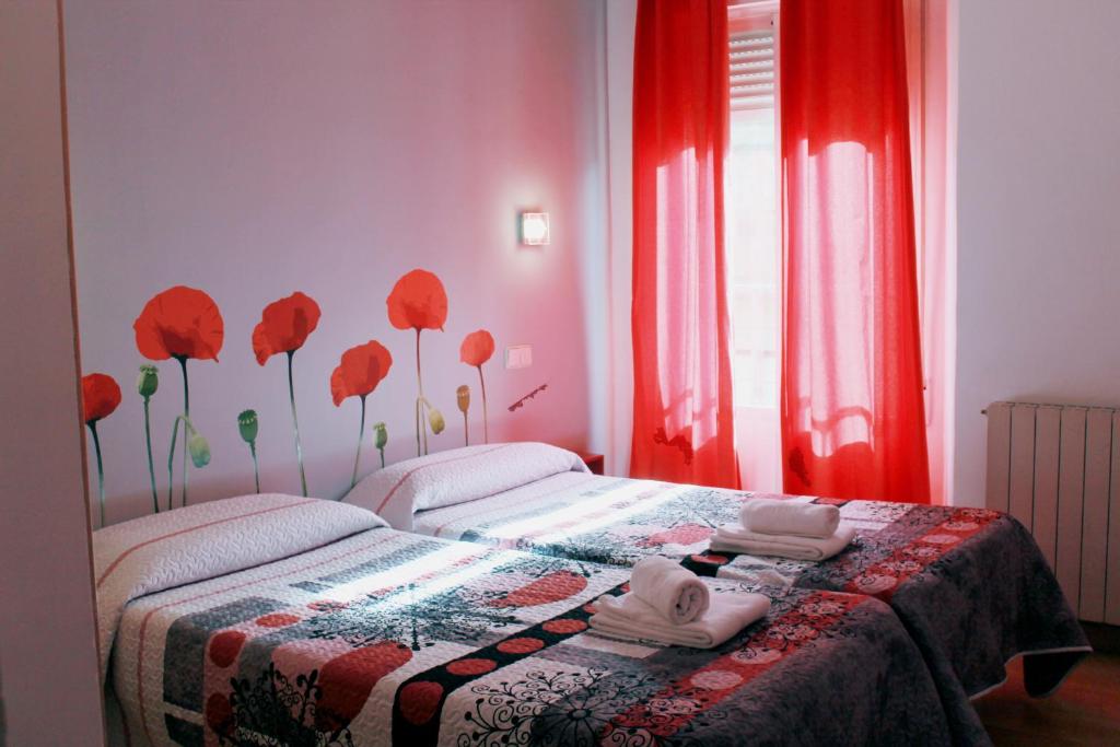 a bedroom with a bed with red curtains and red flowers on it at Hostal Inter Plaza Mayor in Madrid