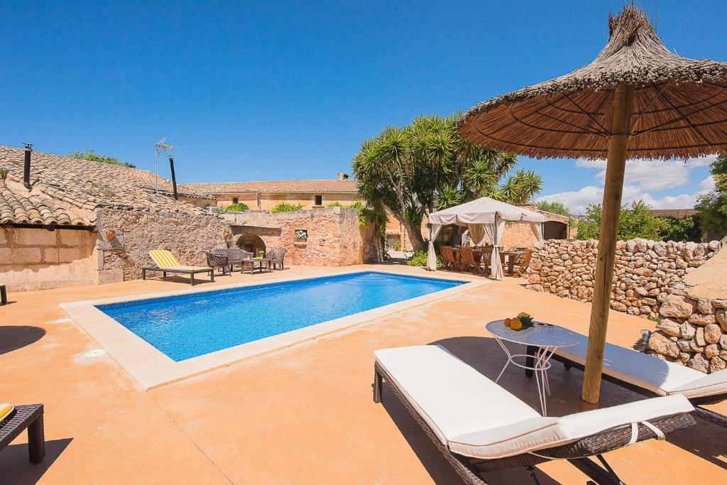 a swimming pool with an umbrella and chairs and a table at Son Caldés in Llucmajor