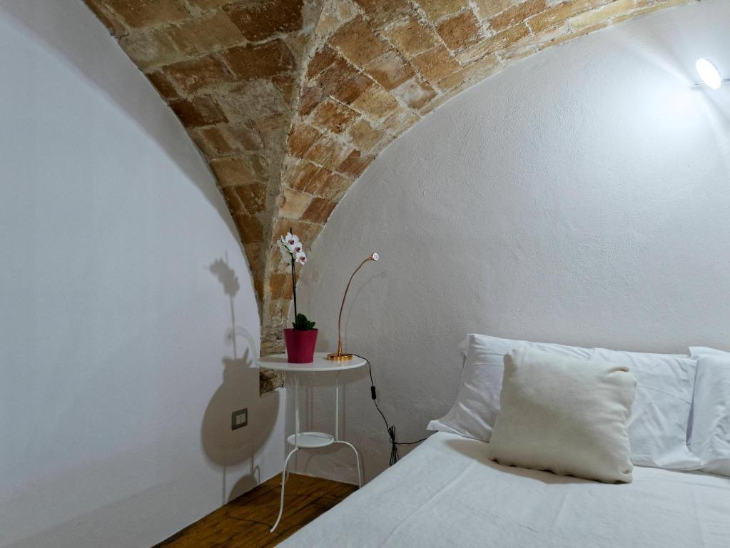 a bedroom with a white bed and a brick wall at Loft 34 in Tarquinia