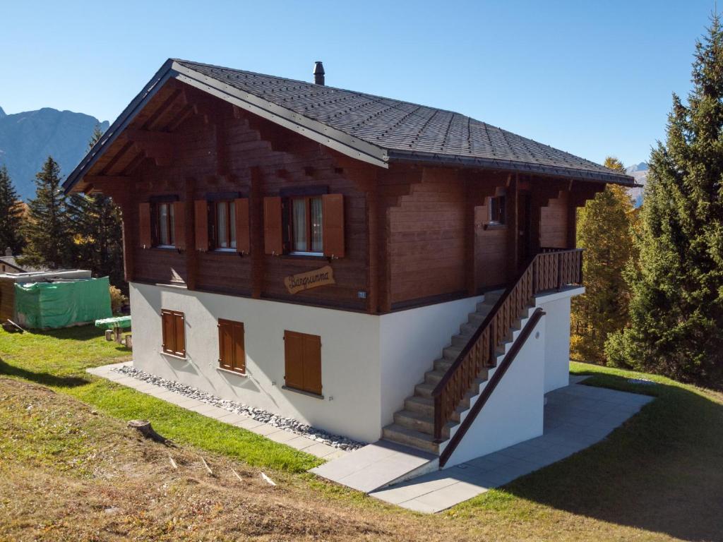a small wooden house with a staircase in a field at Chalet Bärgsunna in Rosswald