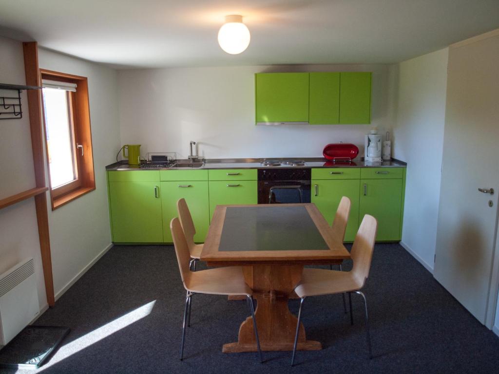 RosswaldにあるChalet Bergfinkのキッチン(緑のキャビネット、木製テーブル、椅子付)