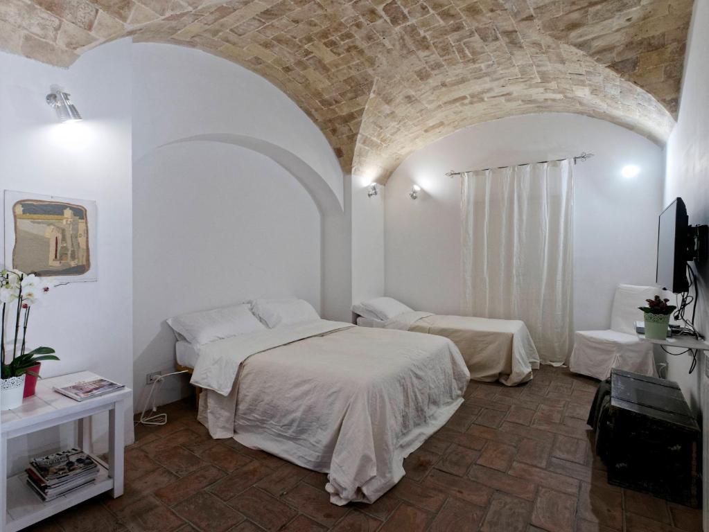 タルクイーニアにあるLe Stalle del Seminarioの石壁のベッドルーム1室(ベッド2台付)