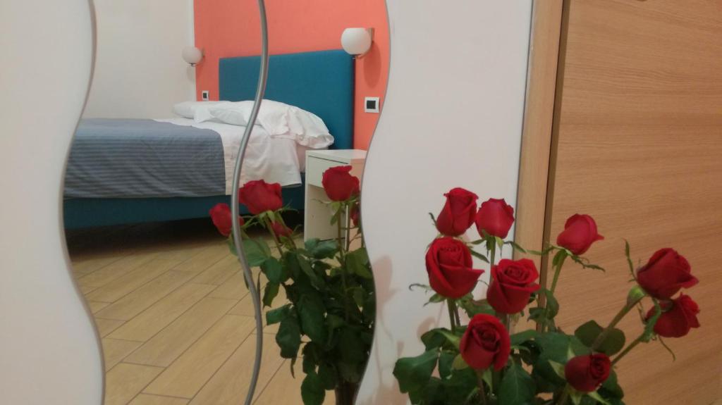 ナポリにあるボヴィオ モダン スイートのベッド付きの客室に赤いバラが一束