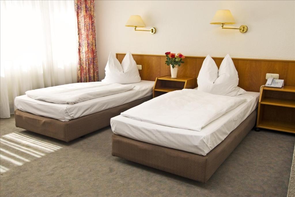 two beds in a hotel room with white sheets at Hotel Stiftswingert in Mainz
