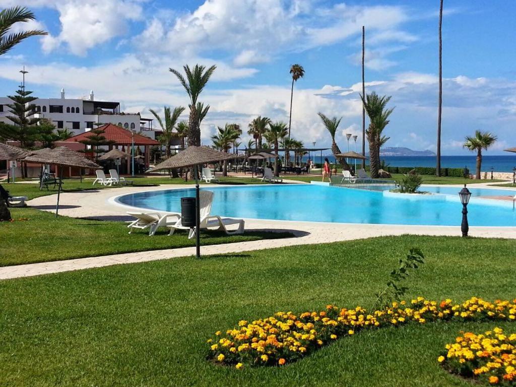 a resort with a swimming pool and flowers in the grass at Marina Beach Appartements in Restinga Smir