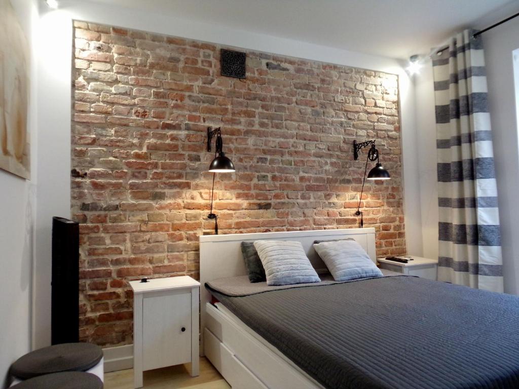 ワルシャワにあるSpichlerz II Old Town Apartmentのレンガの壁とベッドが備わるベッドルーム1室が備わります。