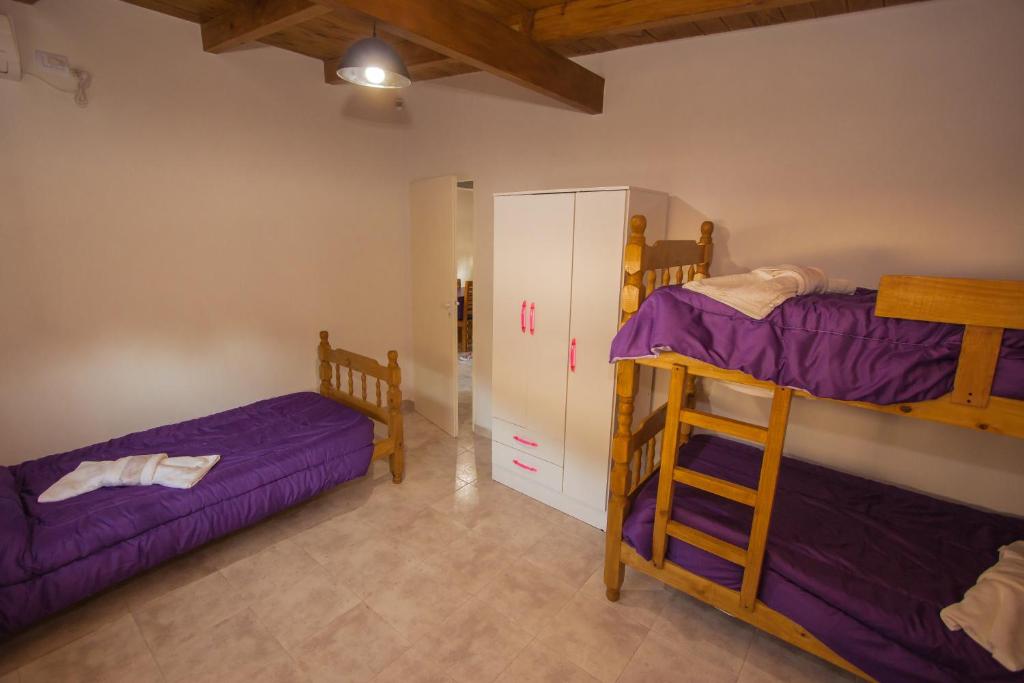 two bunk beds in a room with purple sheets at Maliva Cabanas in La Falda