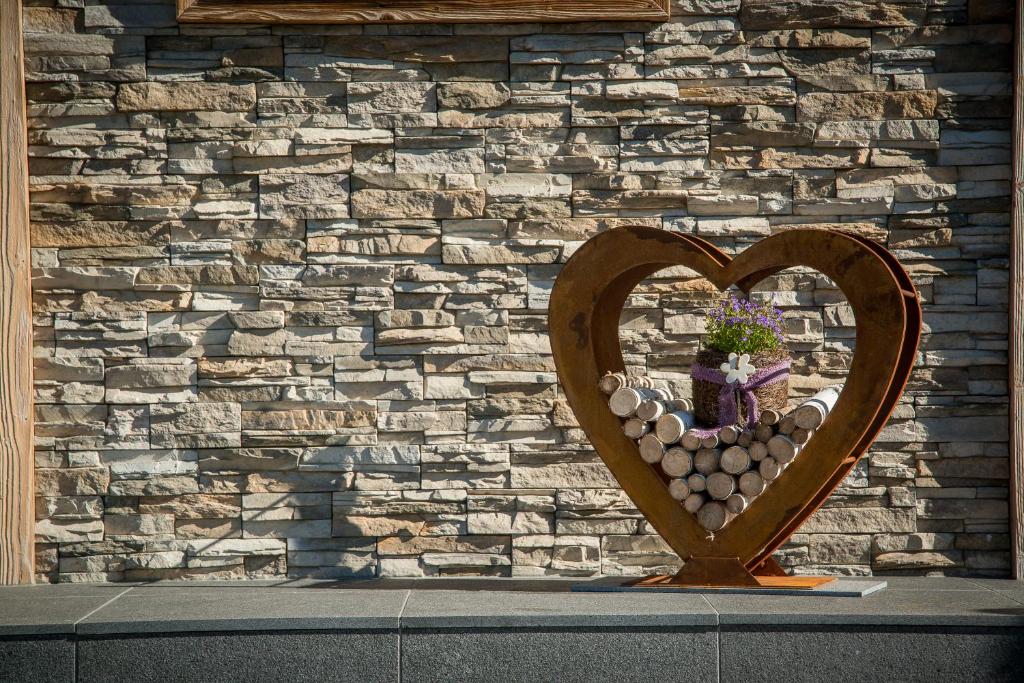 a wooden heart with a vase in front of a stone wall at Gästehaus Hain in Hochfilzen