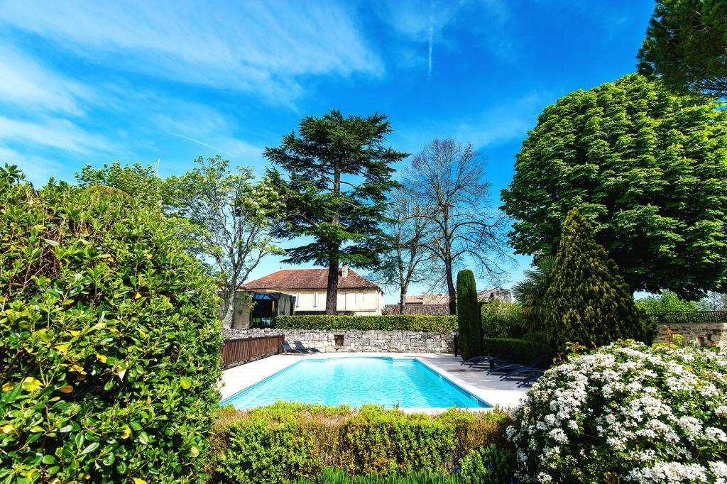 a swimming pool in a garden with bushes at Hôtel Au Logis des Remparts in Saint-Émilion