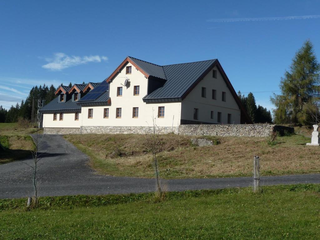 uma grande casa branca numa colina com uma estrada em EA Apartmány na Filipce em Modrava