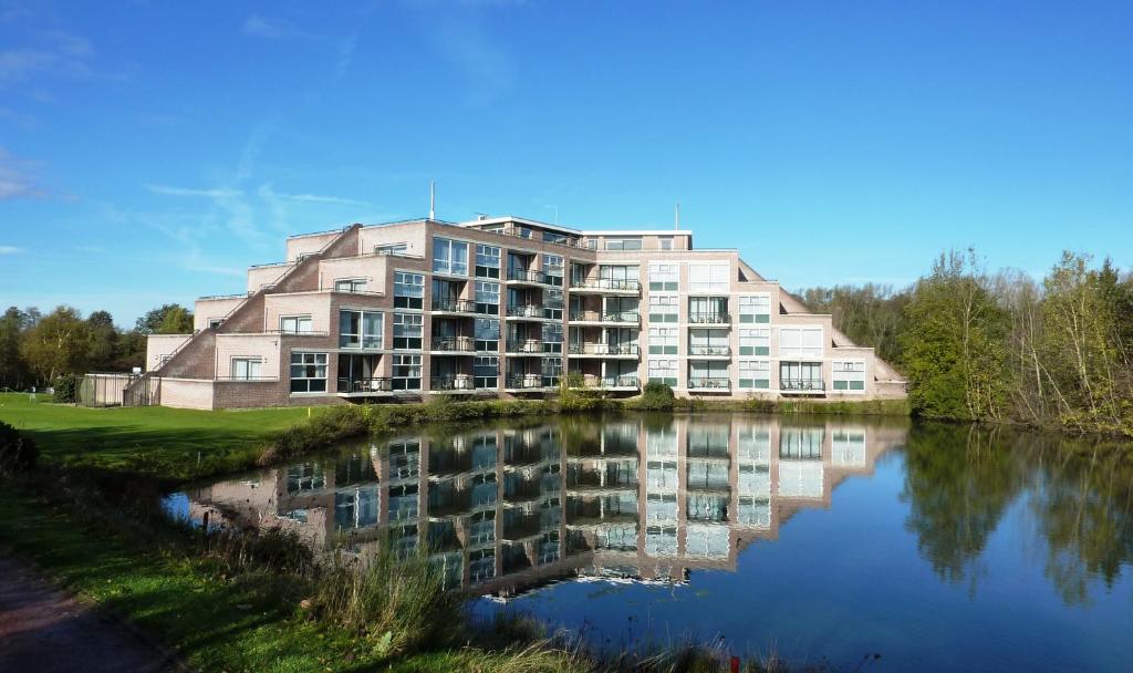 - un grand bâtiment à côté d'une étendue d'eau dans l'établissement Golf-Resort Brunssummerheide, à Brunssum