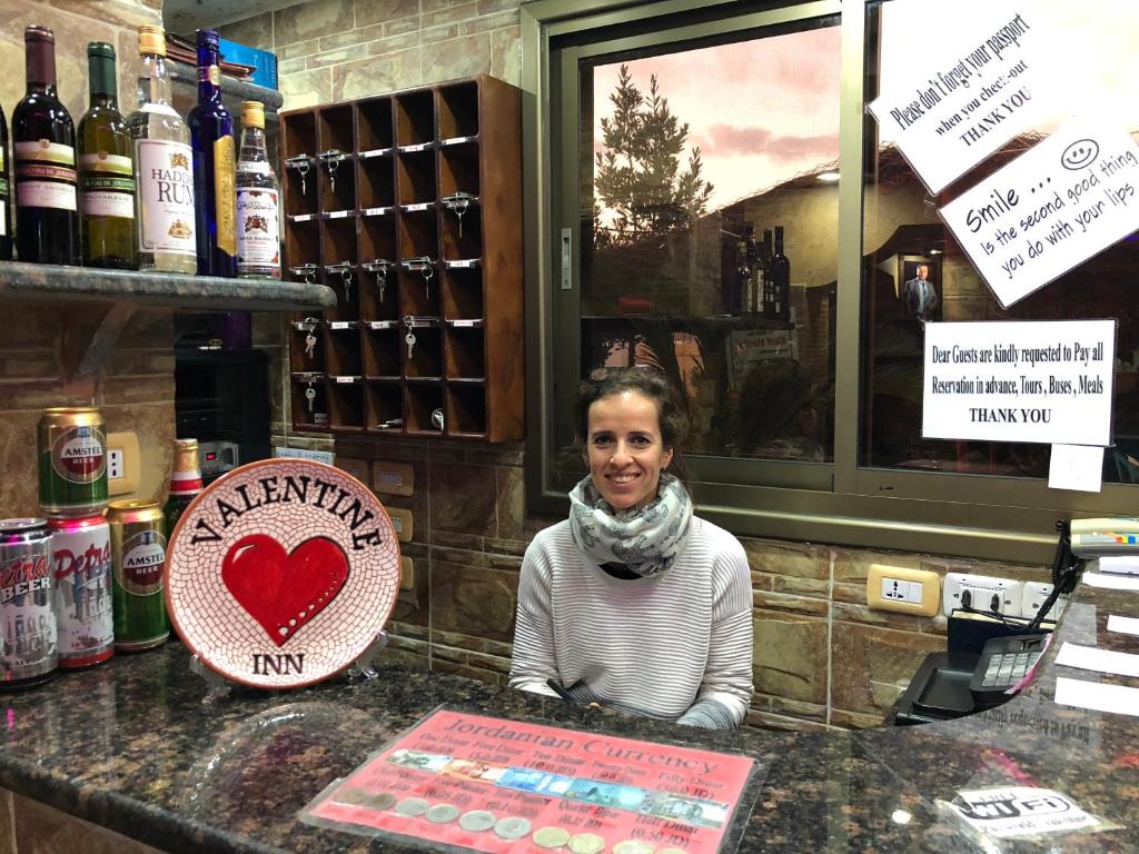 Una donna in piedi dietro un bancone in un wine bar di Valentine Inn a Wadi Musa