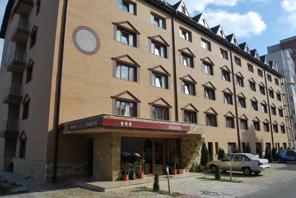 a large brick building with a car parked in front of it at Arion Hotel in Constanţa