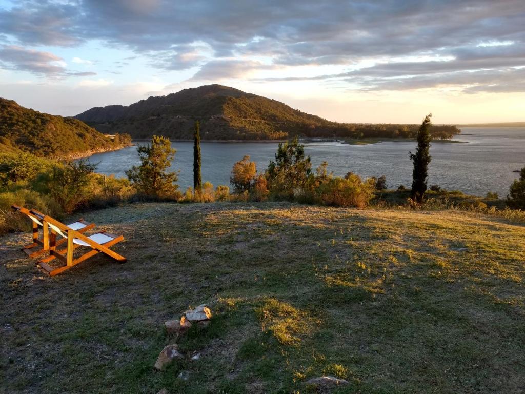 un banco sentado en la parte superior de un campo junto a un lago en Peperina Lago Los Molinos en Villa Ciudad de America