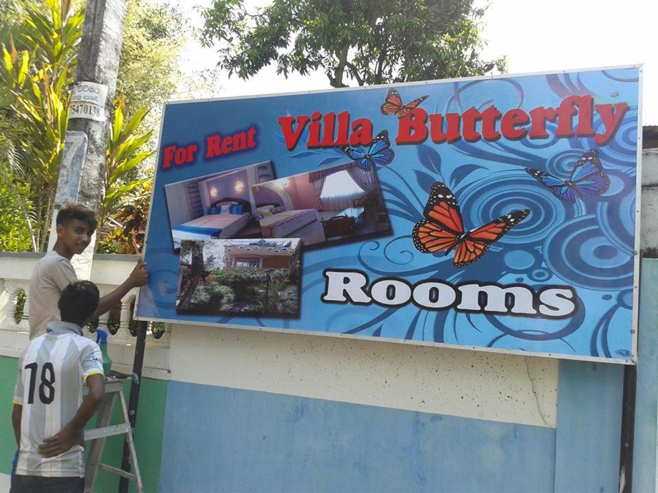 two boys are painting a sign for a butterfly room at Villa Butterfly in Moragalla