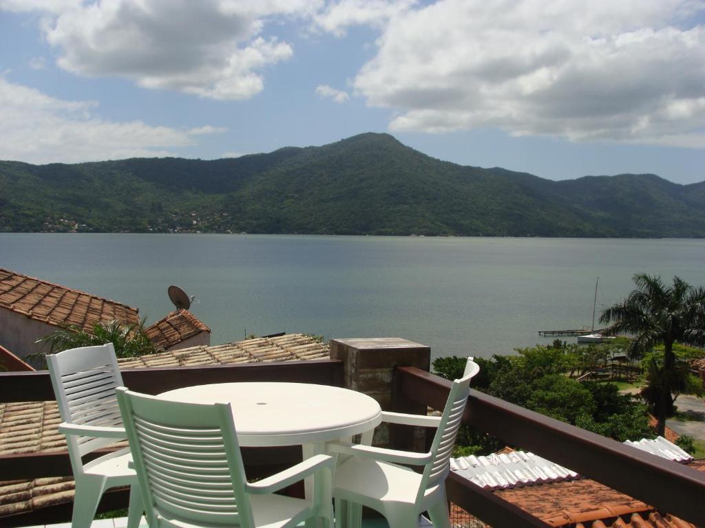 a table and chairs on a balcony with a view of a lake at Residencial Marcelo e Irene in Florianópolis