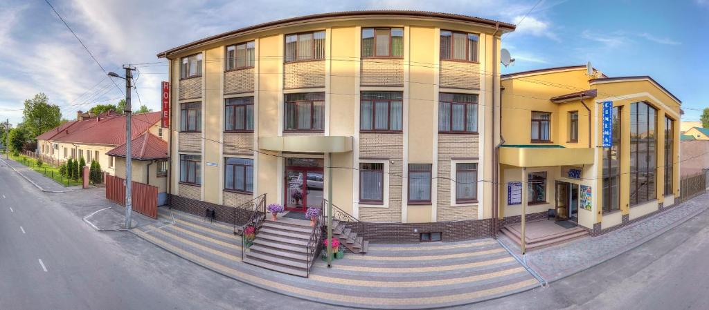 a yellow building with stairs in front of a street at Nashe Misto Guest House in Kovel