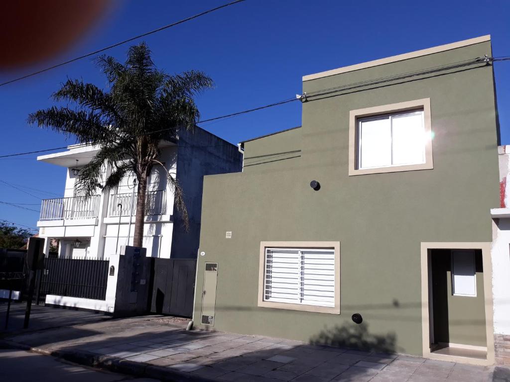 un edificio verde con una palmera delante en Navarro Departamentos Temporarios en Navarro