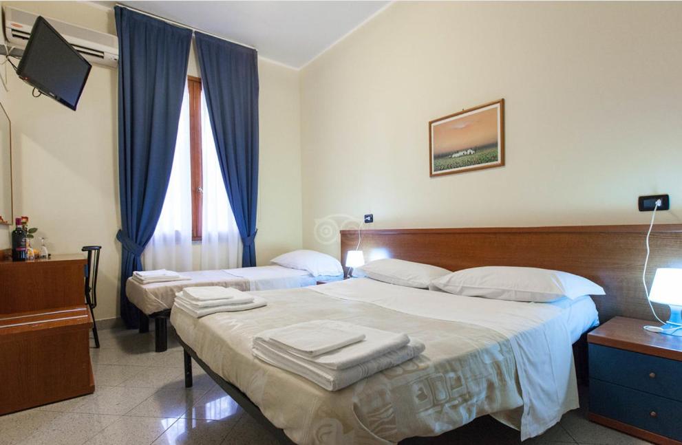 1 dormitorio con 2 camas con cortinas azules en Hotel Greco, en Milán