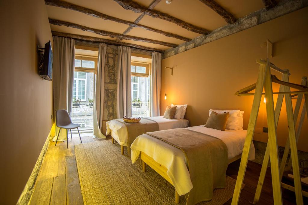 a hotel room with two beds and a window at Laurear Guest House in Porto