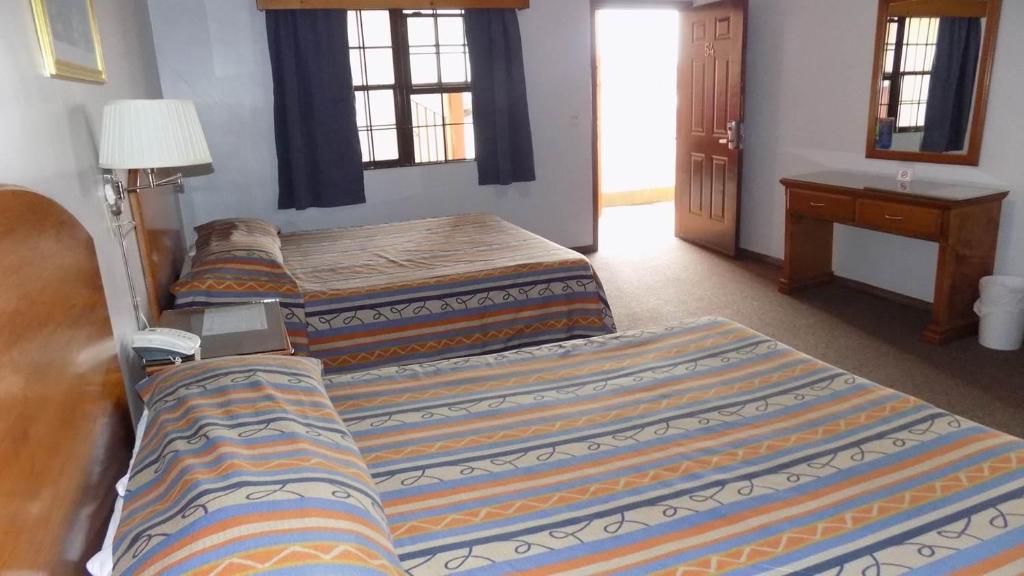 a bedroom with three beds and a table with a lamp at Hotel del Camino in Cuauhtémoc