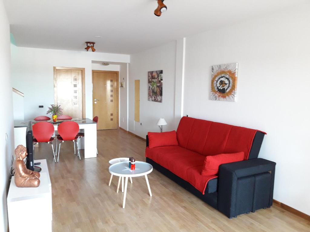 sala de estar con sofá rojo y mesa en Big and Bright Apartment, en Corralejo