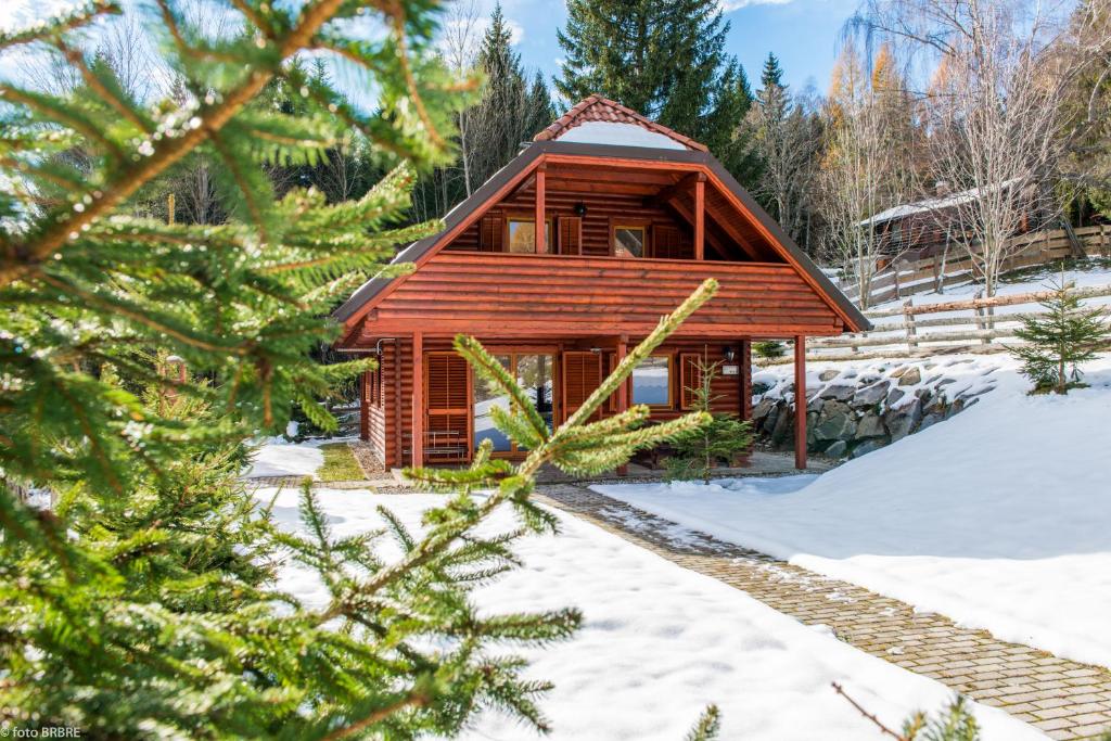 una cabaña de madera en la nieve con un árbol en Koča na Planini, en Planina pod Sumnikom