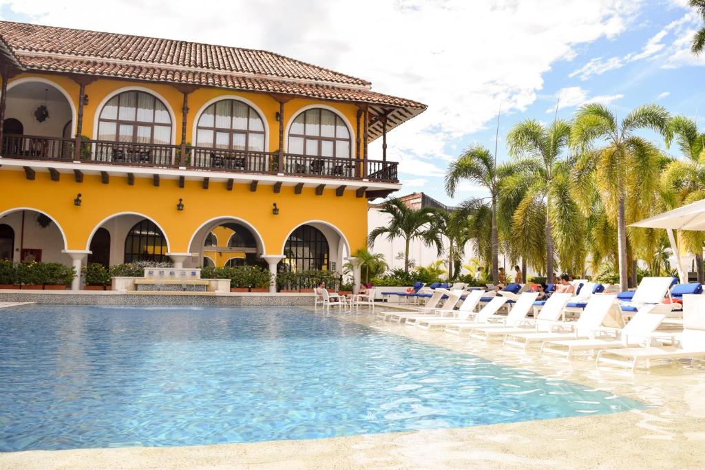 a resort pool with lounge chairs and a building at Hotel Union in Girardot