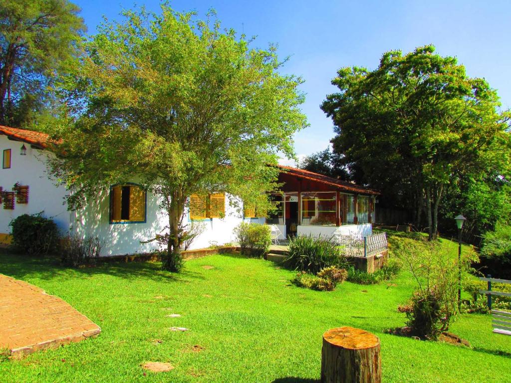 uma pequena casa branca com uma árvore no quintal em Pousada Pe da Serra em Tiradentes