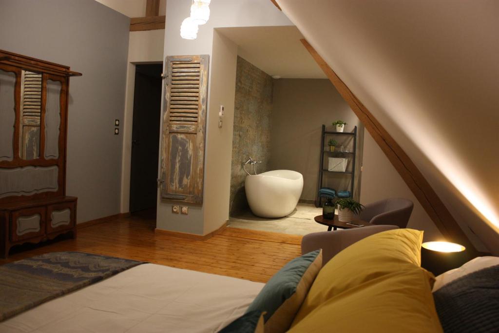 a living room with a bed and a bath tub at Théière & Couverts - Les Chambres in Cernay