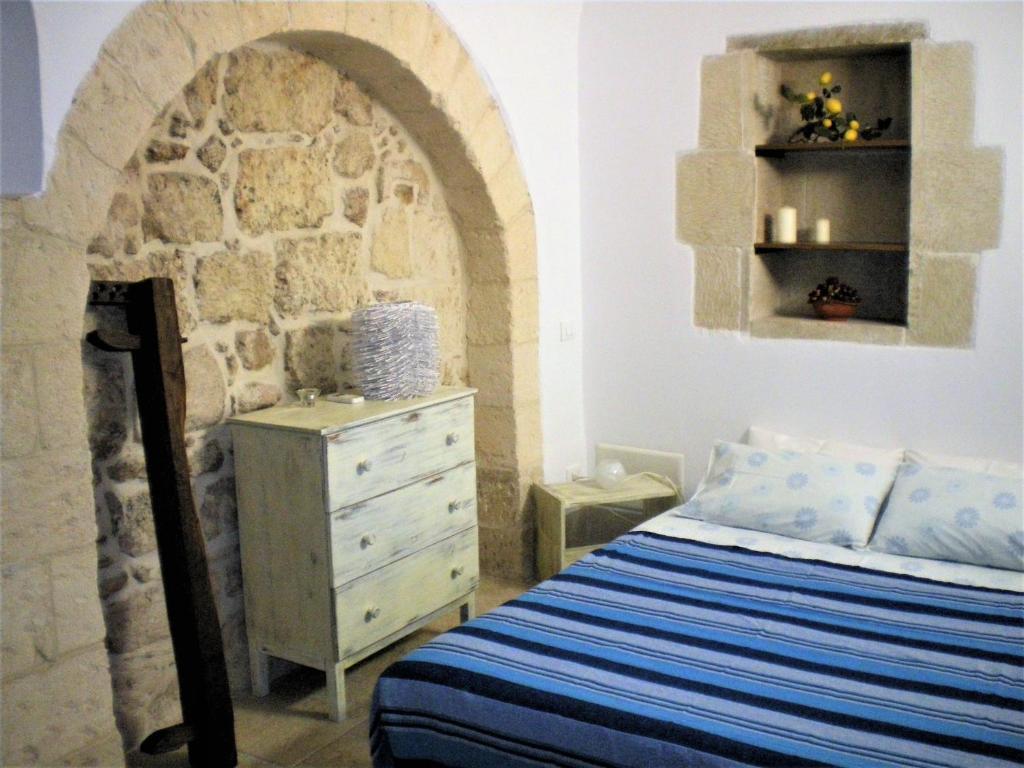 a bedroom with a bed and a stone wall at La Corte dei Messapi in Muro Leccese