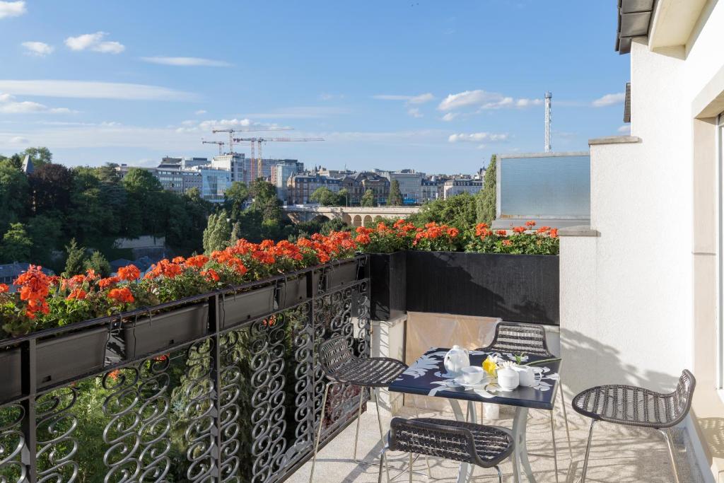a balcony with a table and chairs and flowers at The Queen Luxury Apartments - Villa Vinicia in Luxembourg