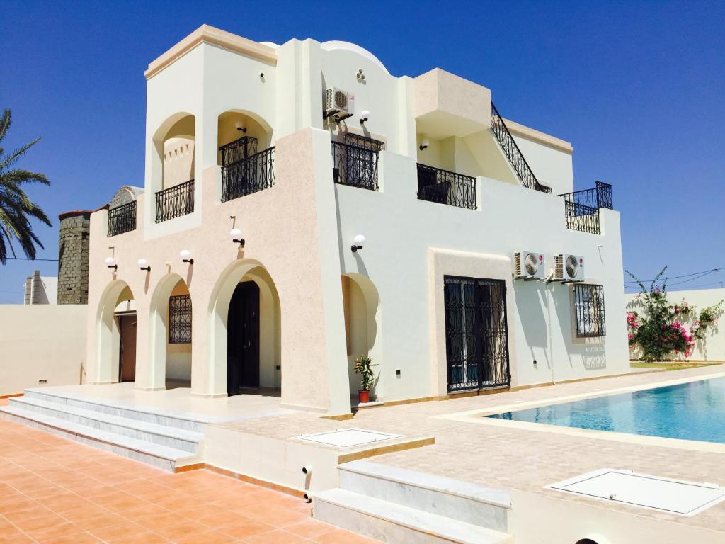 uma casa branca com uma piscina em frente em Villa Tezdain em Houmt Souk
