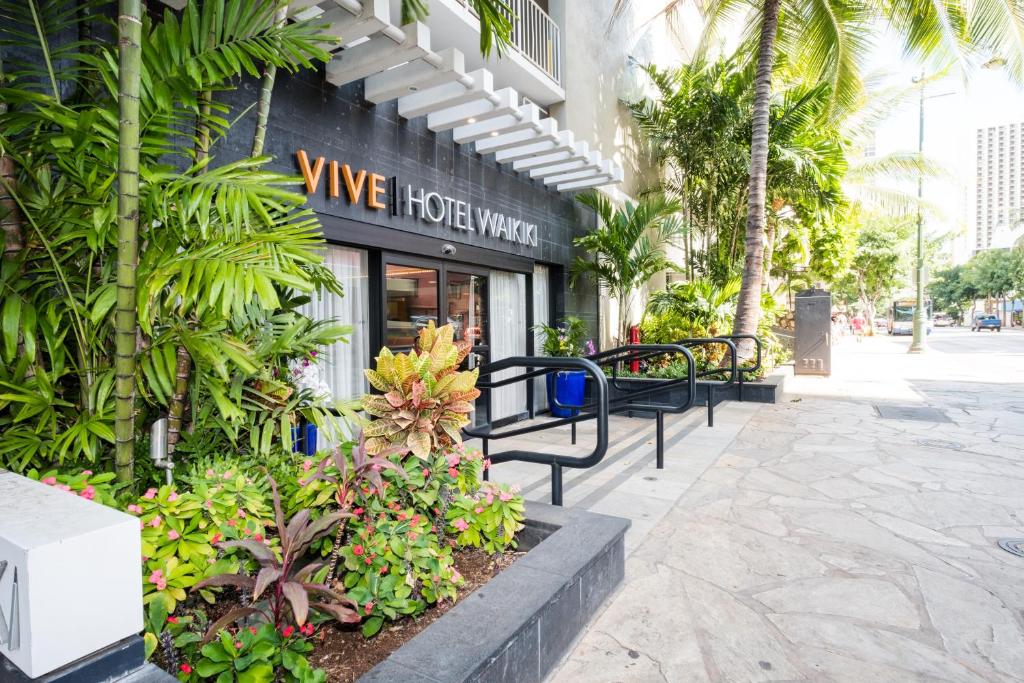 uma fachada de uma loja com bancos e plantas em VIVE Hotel Waikiki em Honolulu