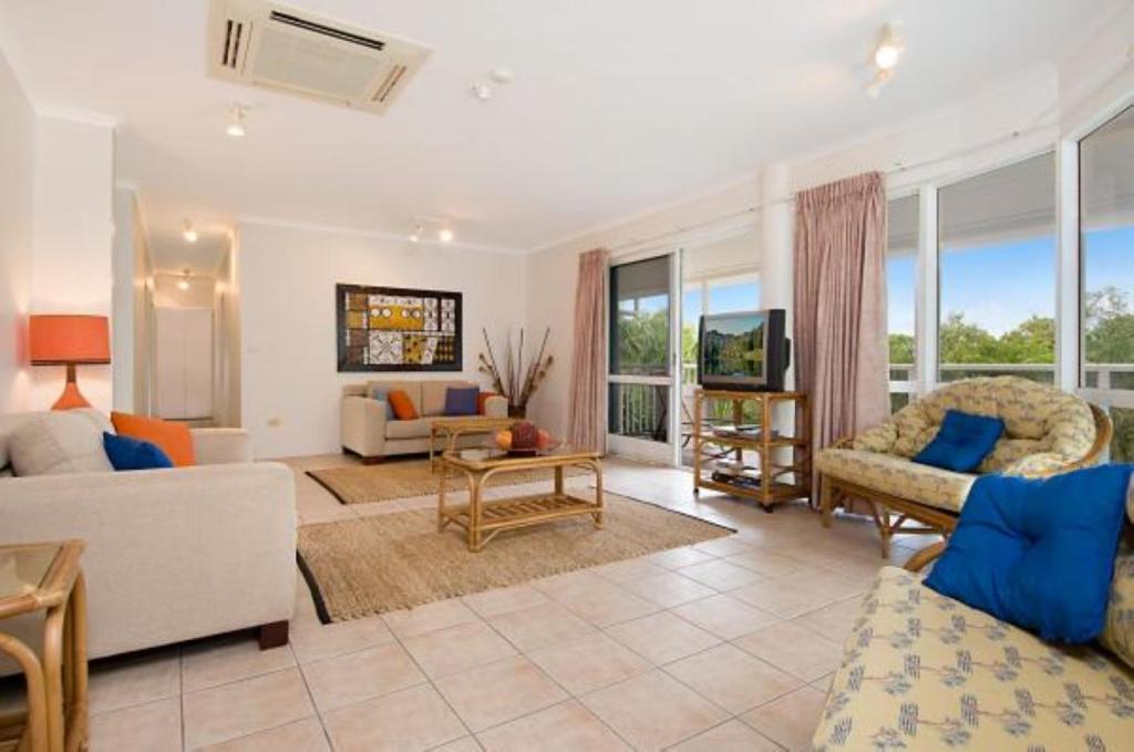 a living room with a couch and a table and chairs at Palm Cove Penthouse in Palm Cove
