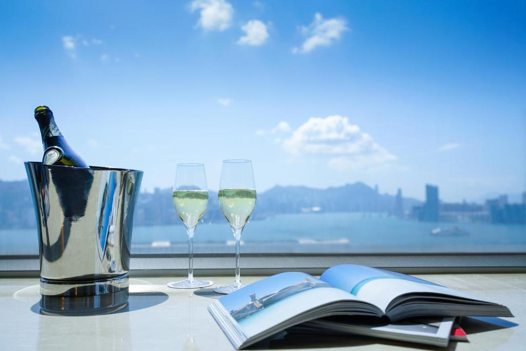 uma mesa com dois copos de vinho e um livro aberto em Hotel COZi Harbour View em Hong Kong