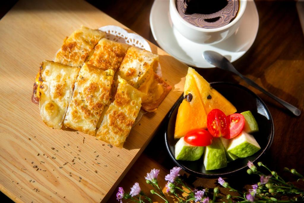 a wooden table with a plate of bread and a plate of fruit at Discovery B&amp;B in Linbian